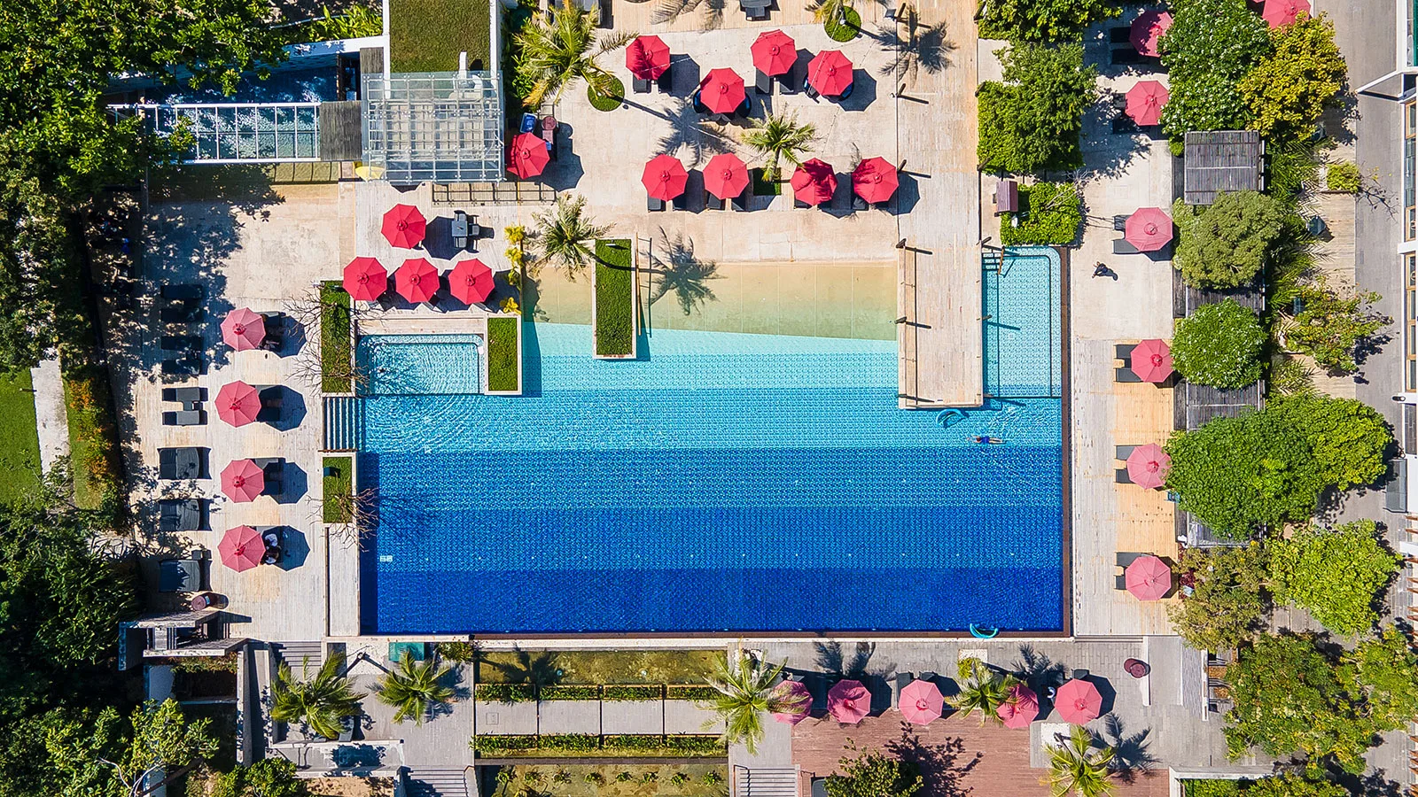 Aerial view of the large pool with red umbrellas and loungers at Amari Hua Hin