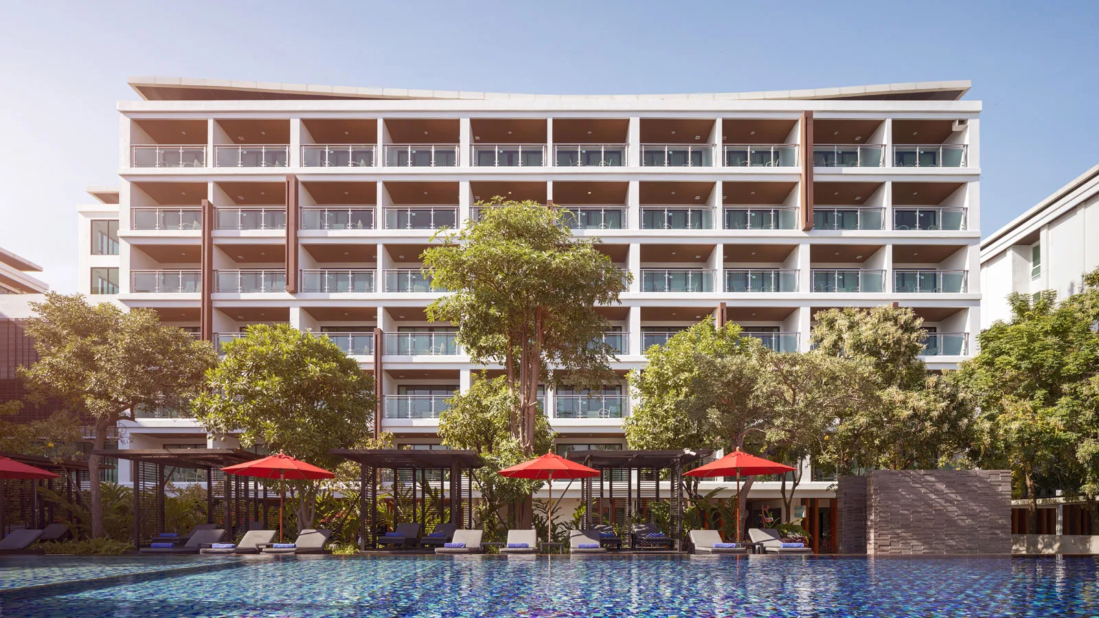 Pool and red umbrellas in front of the guest wing at Amari Hua Hin, Khao Takiab