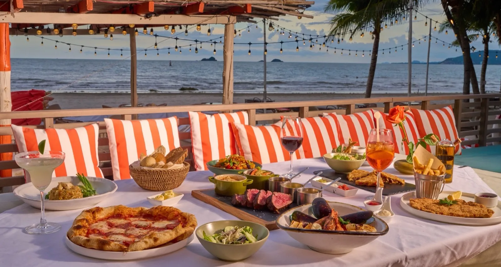 Pizza, salads and cocktails on a beachfront table at Anantasila Beach Restaurant Hua Hin