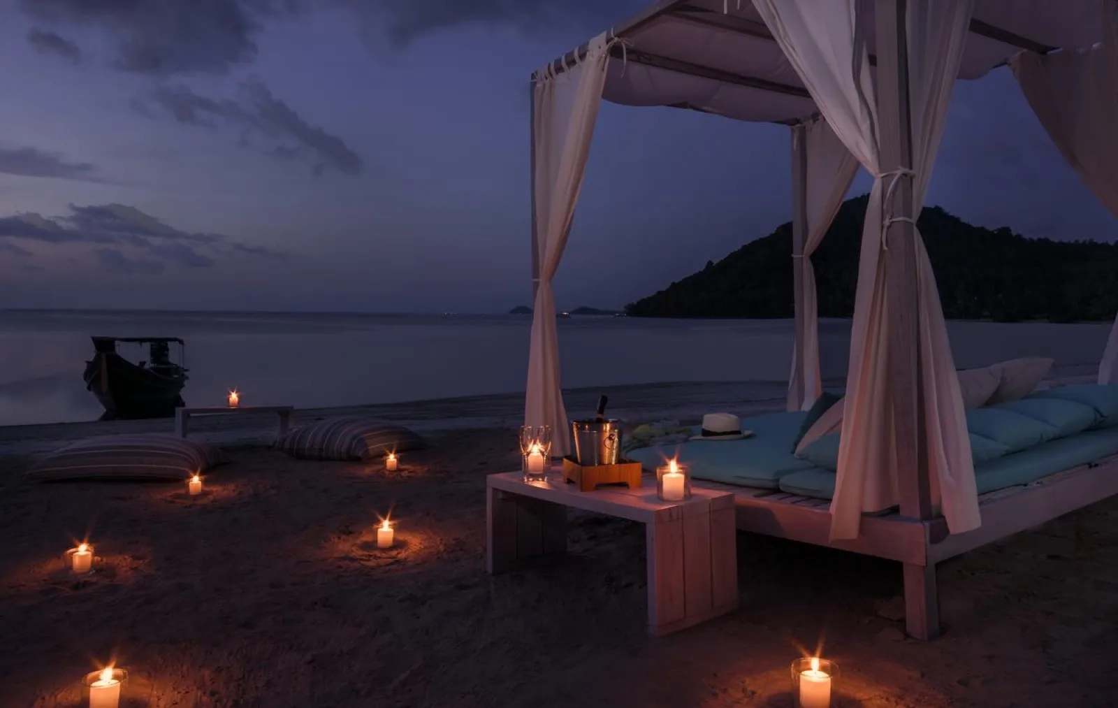 Candlelit beach dining set-up on the sand at Avani+ Samui after sunset