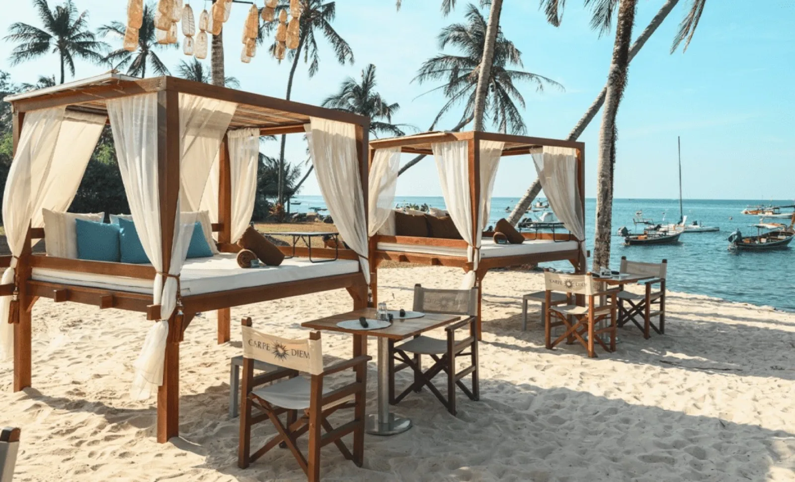 Curtained cabanas on the sand facing Bang Tao Bay at Carpe Diem Beach Club