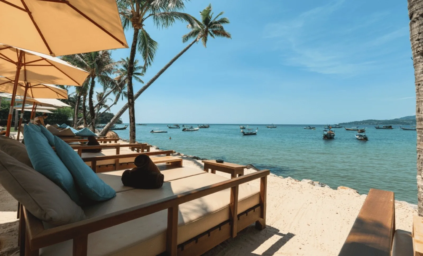Beachfront bed with cushions and umbrella on the sand at Carpe Diem Beach Club Bang Tao