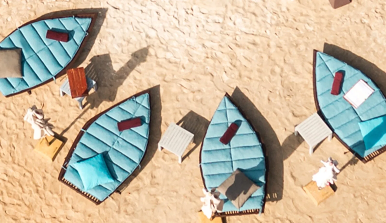 Aerial view of boat-shaped daybeds on the beach at Carpe Diem Beach Club, Bang Tao