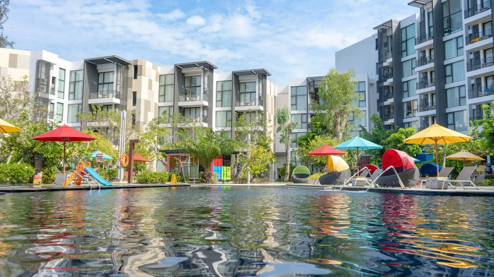 Main pool at Cassia Phuket in Laguna with umbrellas, loungers and the apartment blocks behind