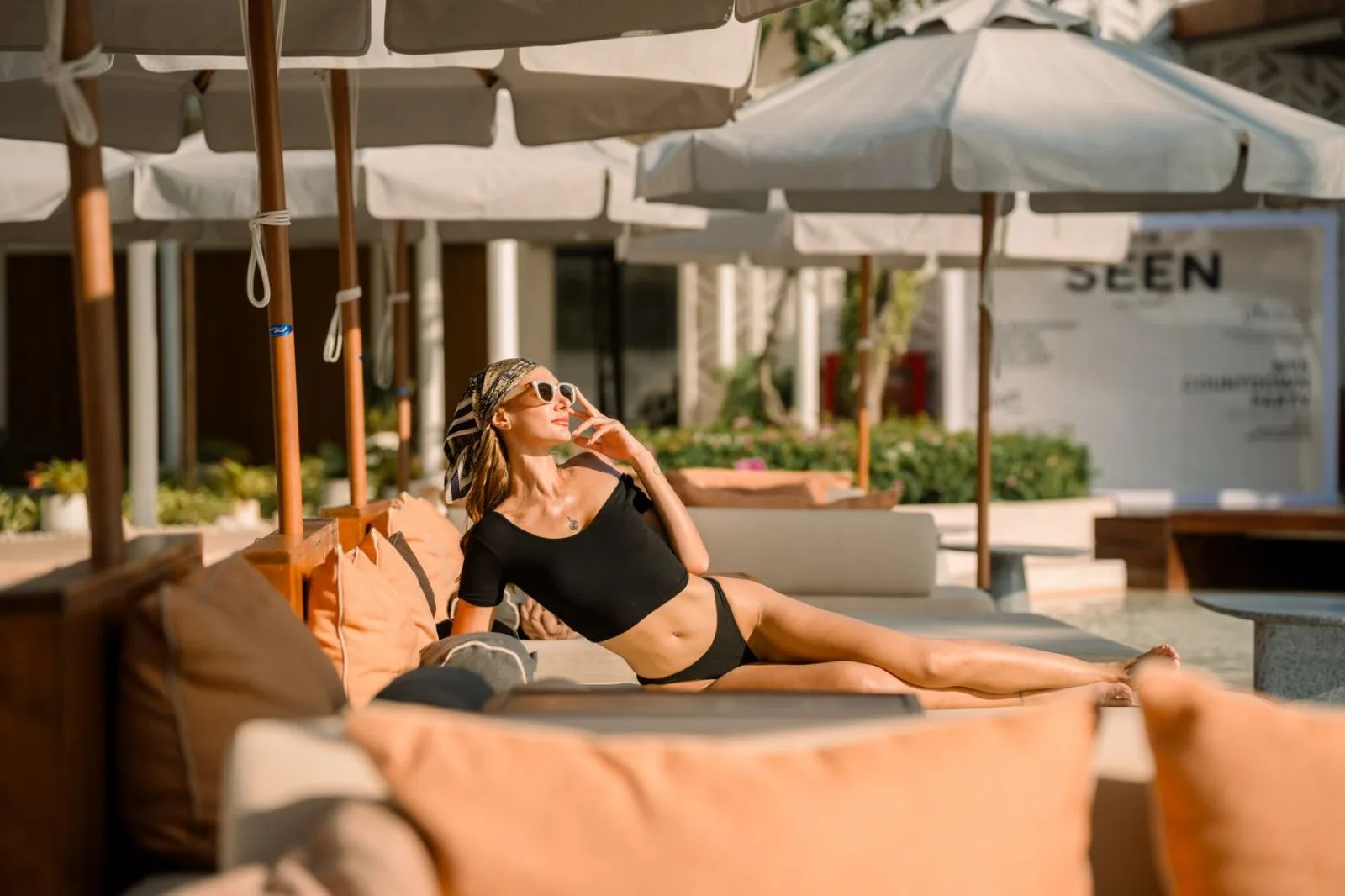 Guest lounging on an outdoor sofa under white umbrellas at CLUB SEEN Koh Samui
