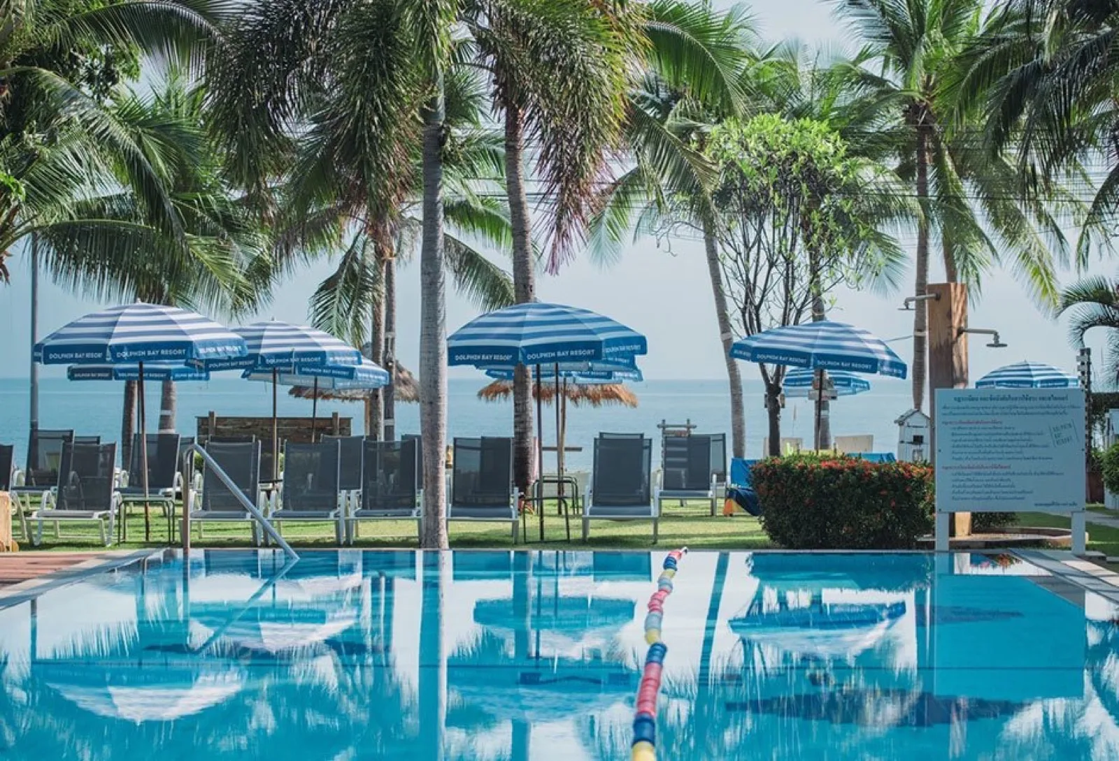 Swimming pool with blue umbrellas and sea view at Dolphin Bay Resort in Sam Roi Yot