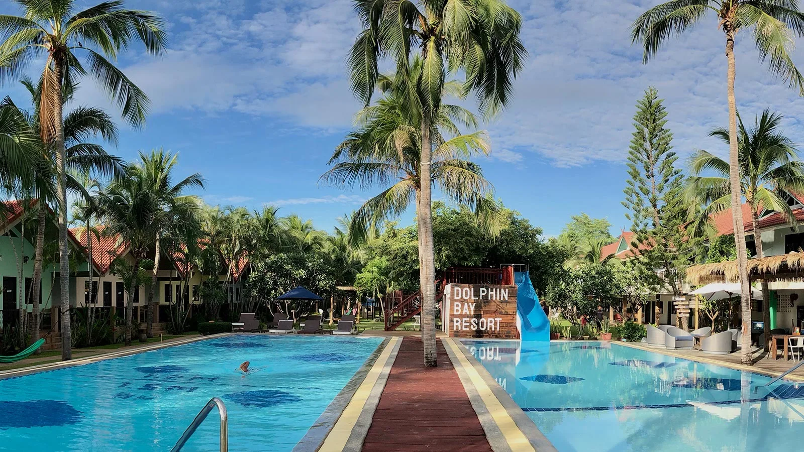 Long pool lined with palms and bungalows at Dolphin Bay Resort