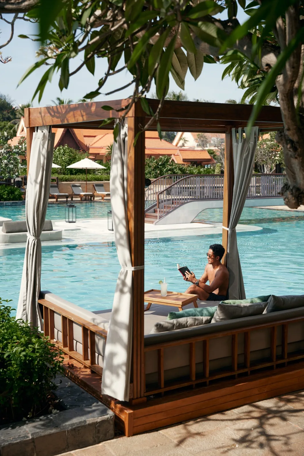 Poolside cabana with a guest reading beside the pool at Dusit Thani Hua Hin