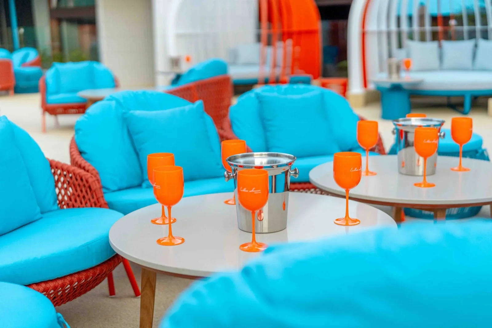 Lounge seating with turquoise chairs and orange glasses at Endless Summer Beach Club