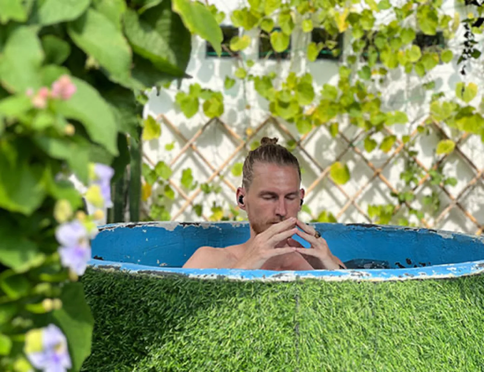 Man sitting in an ice bath surrounded by greenery at Evolve Health Club