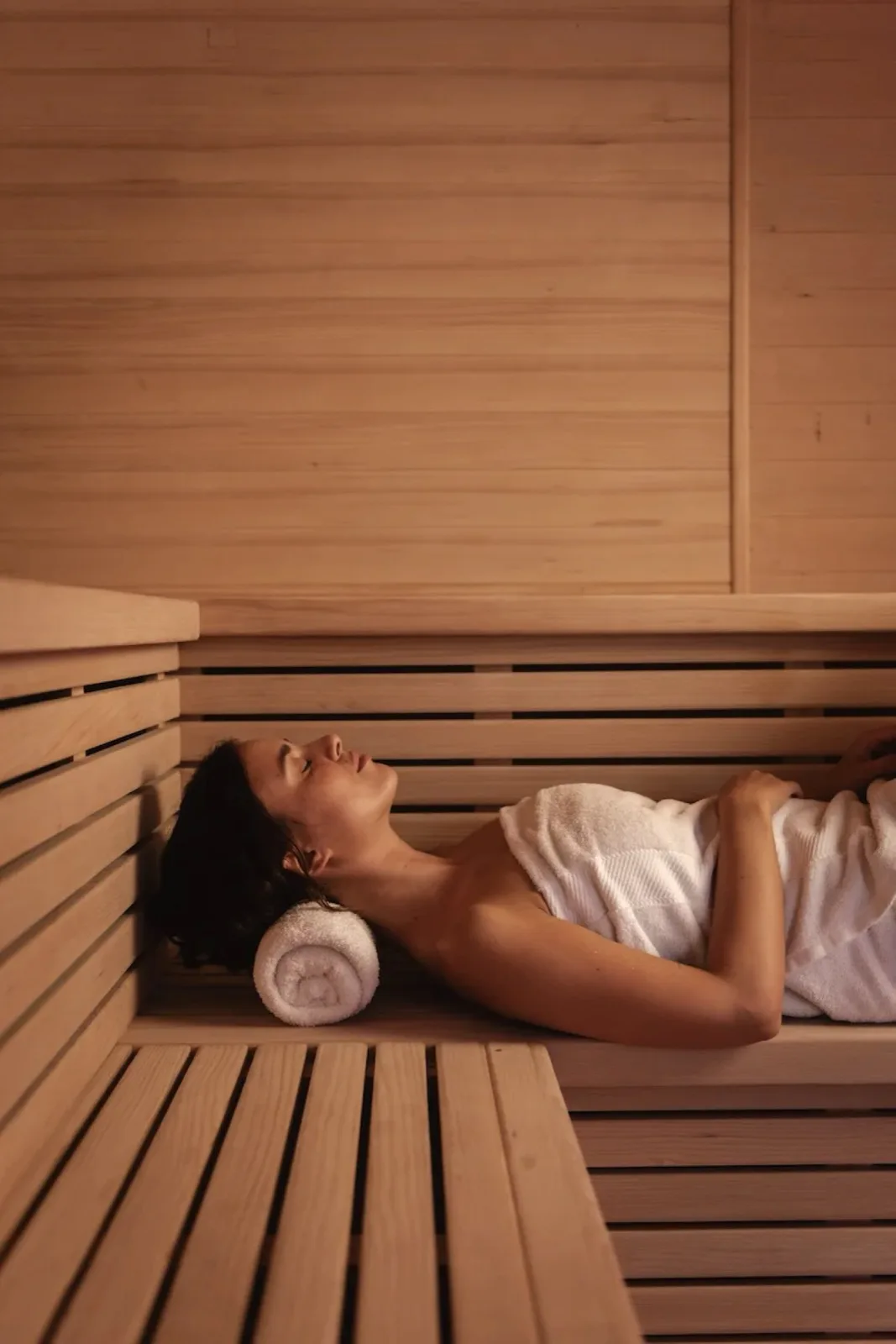 Guest resting on a wooden bench in the sauna at FIRA Recovery Club