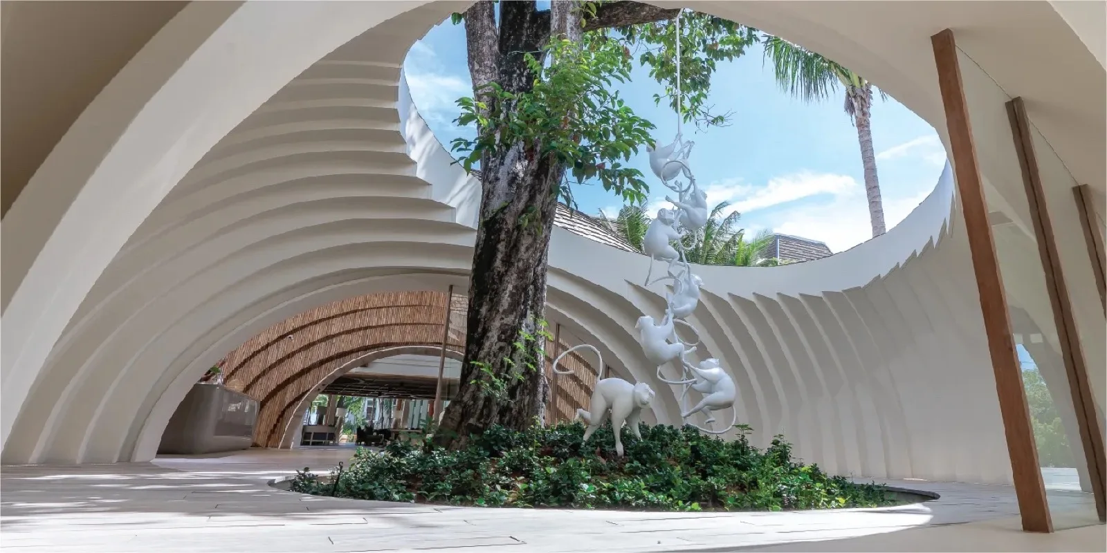 Curved white architecture around a courtyard tree at Holiday Inn Resort Samui Bophut Beach