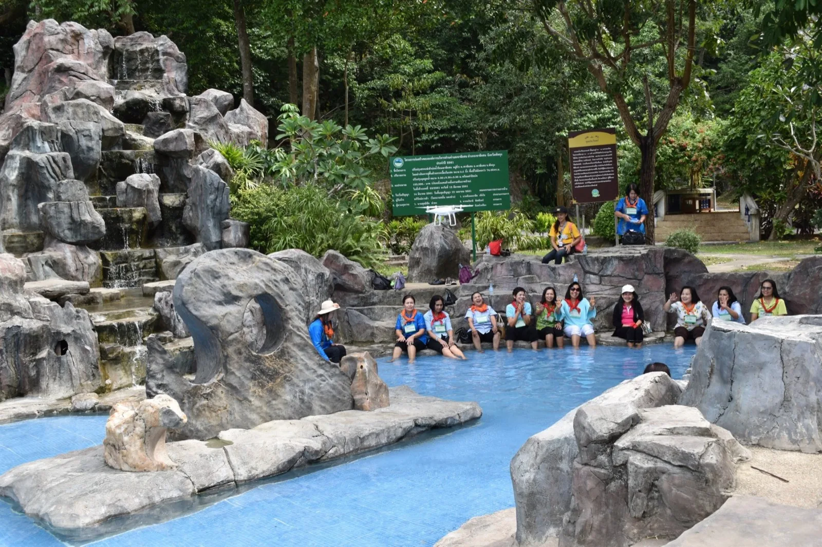 Visitors soaking their feet in the rock-edged warm pool at Khao Chaison Hot Spring, Phatthalung