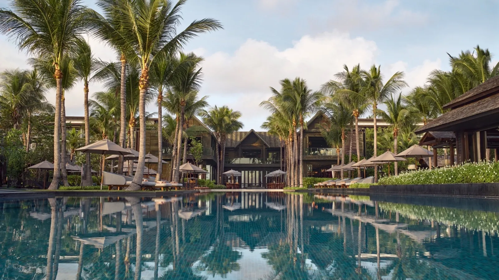 Kimpton Kitalay Samui palm-lined beachfront pool reflecting the resort buildings on Choeng Mon