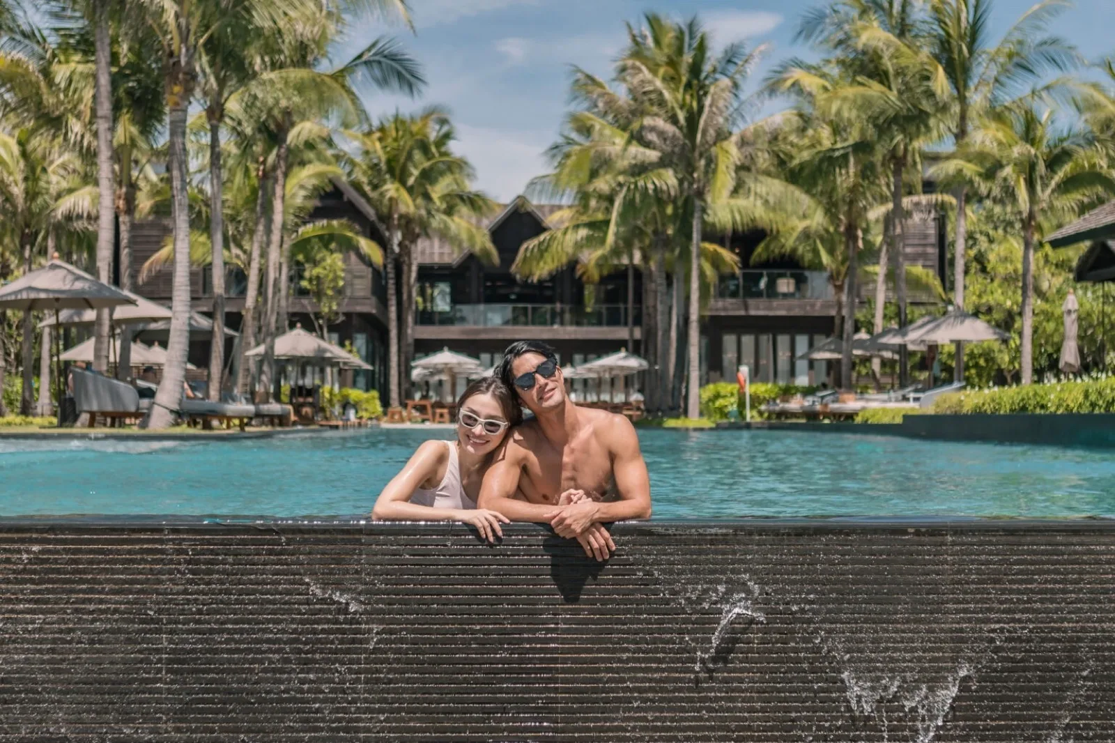 Couple leaning on the edge of the Olympic-size infinity pool at Kimpton Kitalay Samui