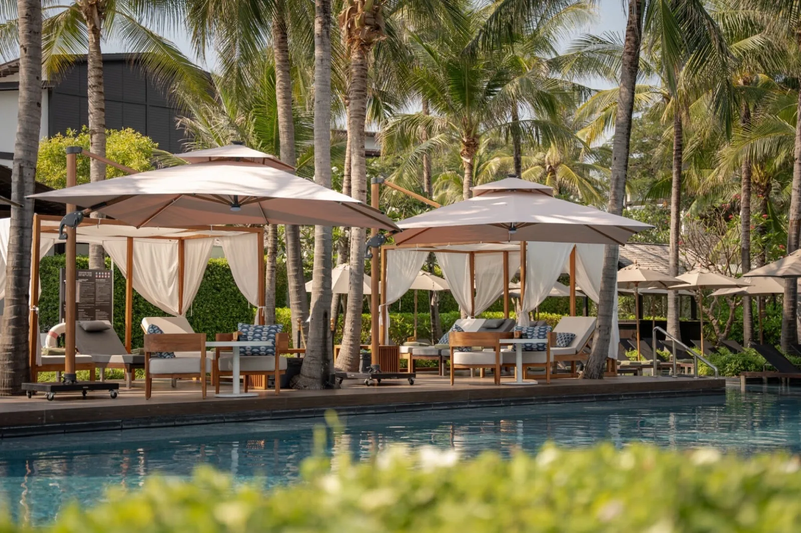 Shaded poolside cabanas and loungers beside the main pool at Kimpton Kitalay Samui