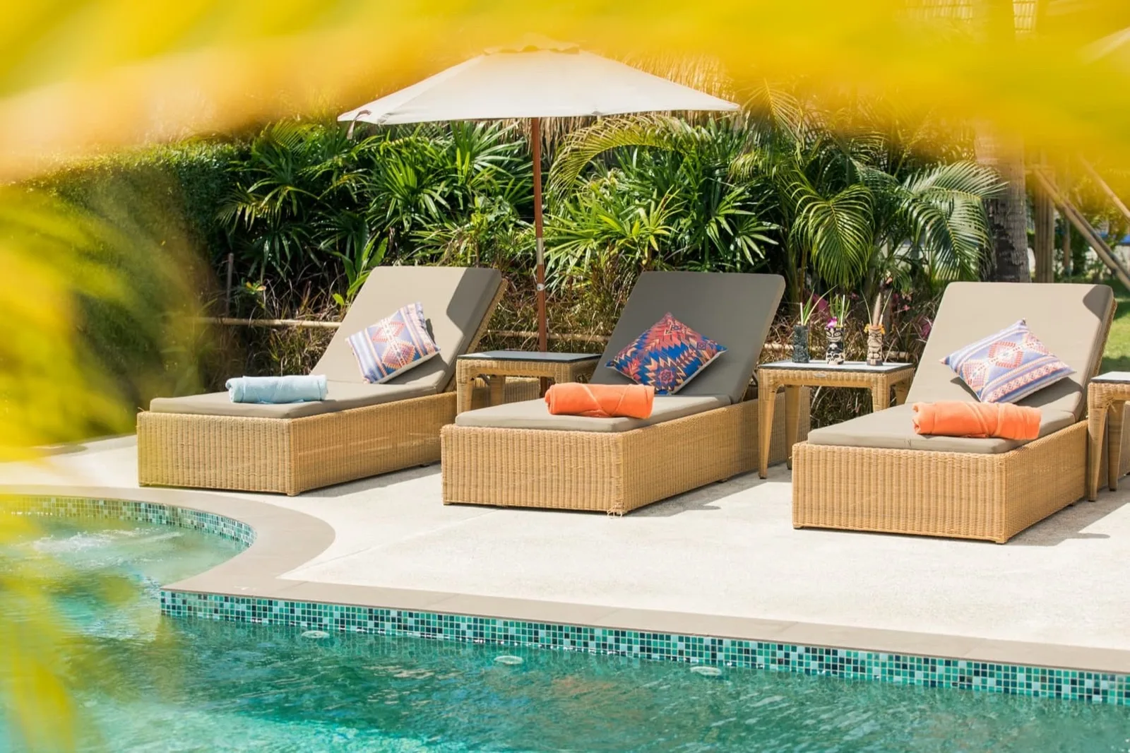 Rattan sun loungers at the edge of the pool in the garden at Maya Resort Samui