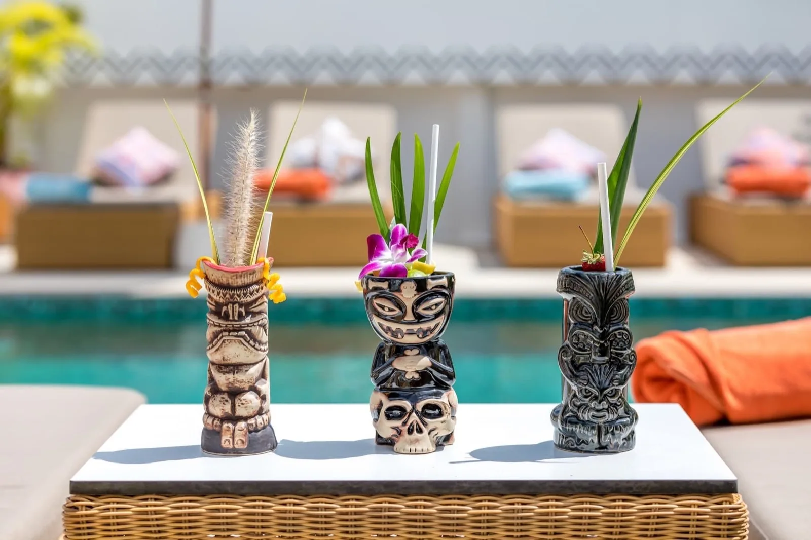 Tiki cocktail cups on a poolside table at Maya Resort Samui