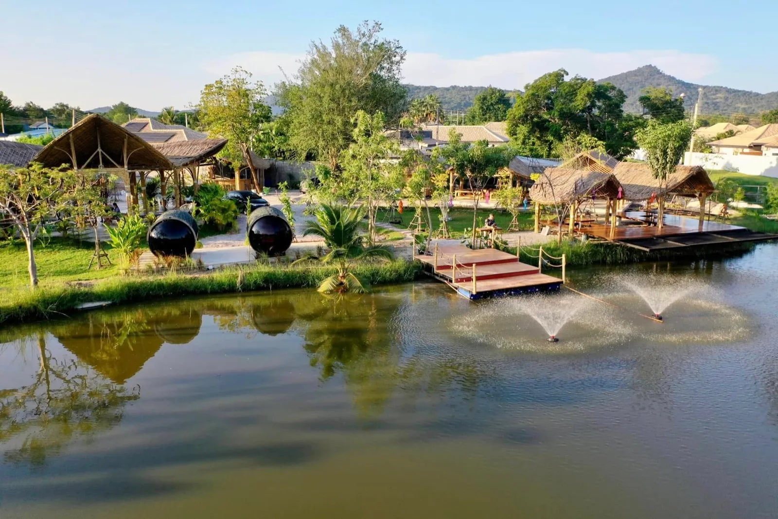 Lake with fountains, wooden decks and thatched salas at Mojo Spa and Retreat in Hua Hin