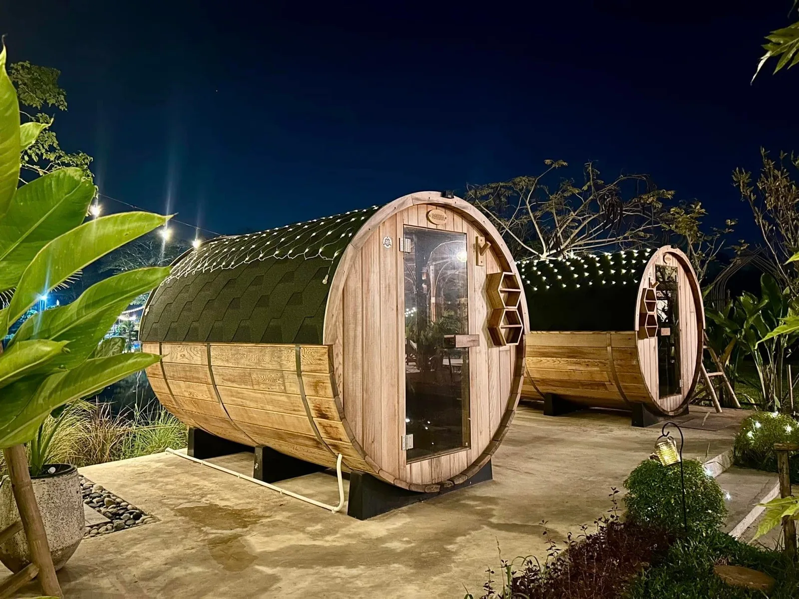 Wooden barrel saunas lit up at night at Mojo Spa and Retreat, Hin Lek Fai