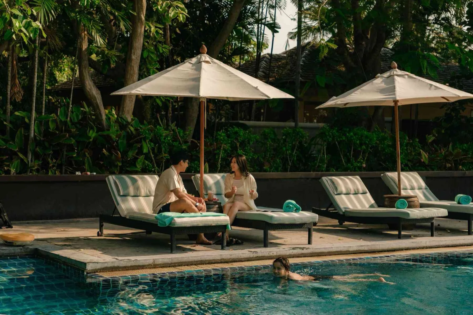Couple on cushioned loungers beside the pool at Mövenpick Asara Hua Hin