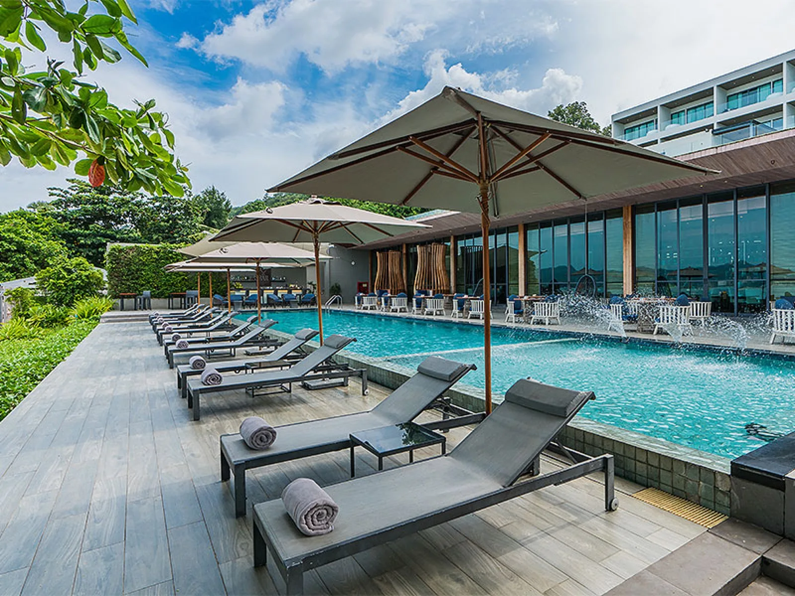 Infinity pool deck at My Beach Resort Phuket with loungers, rolled towels and umbrellas