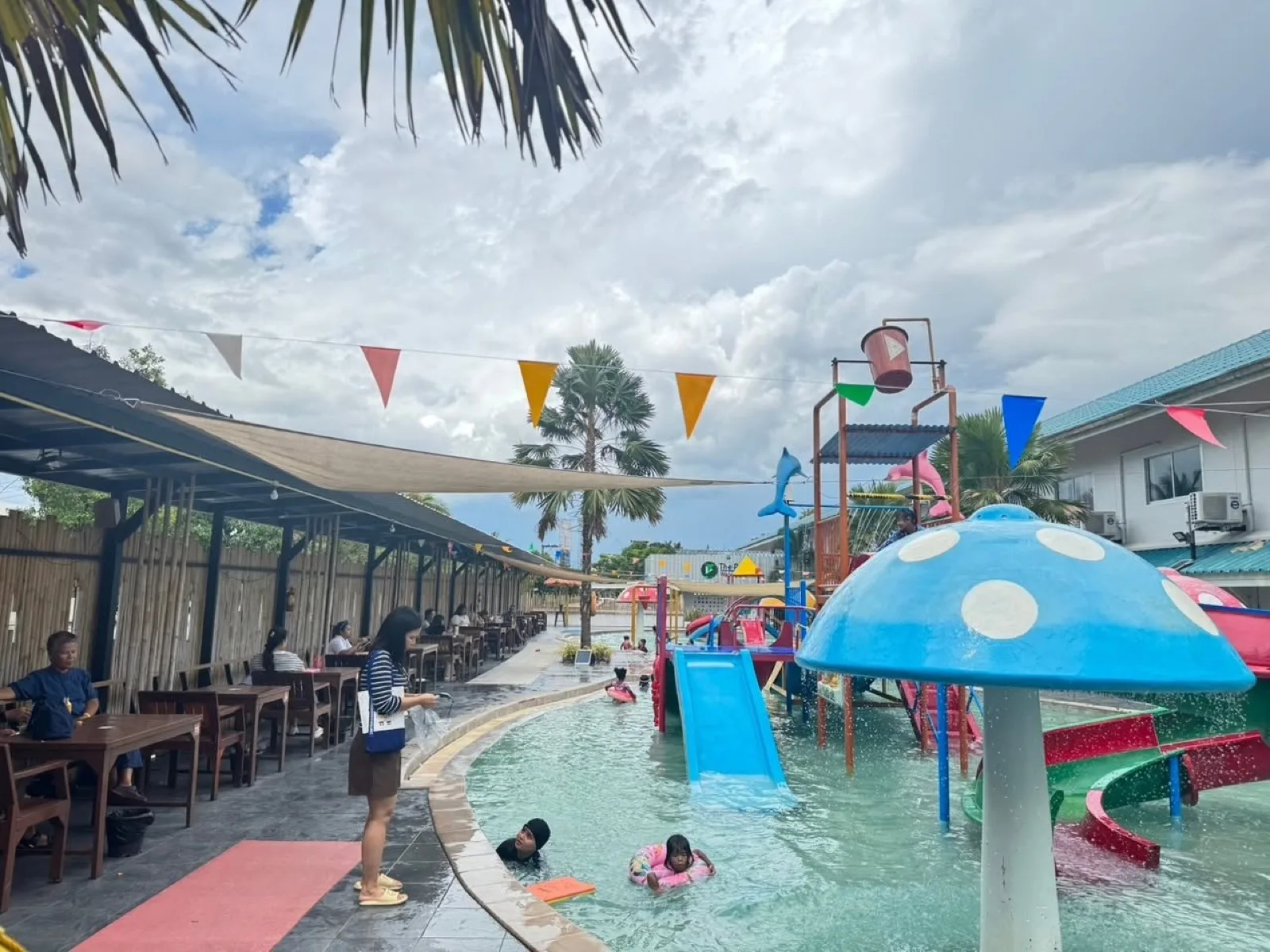 Kids' slides and poolside tables under bunting at The Play Waterpark, Nakhon Si Thammarat