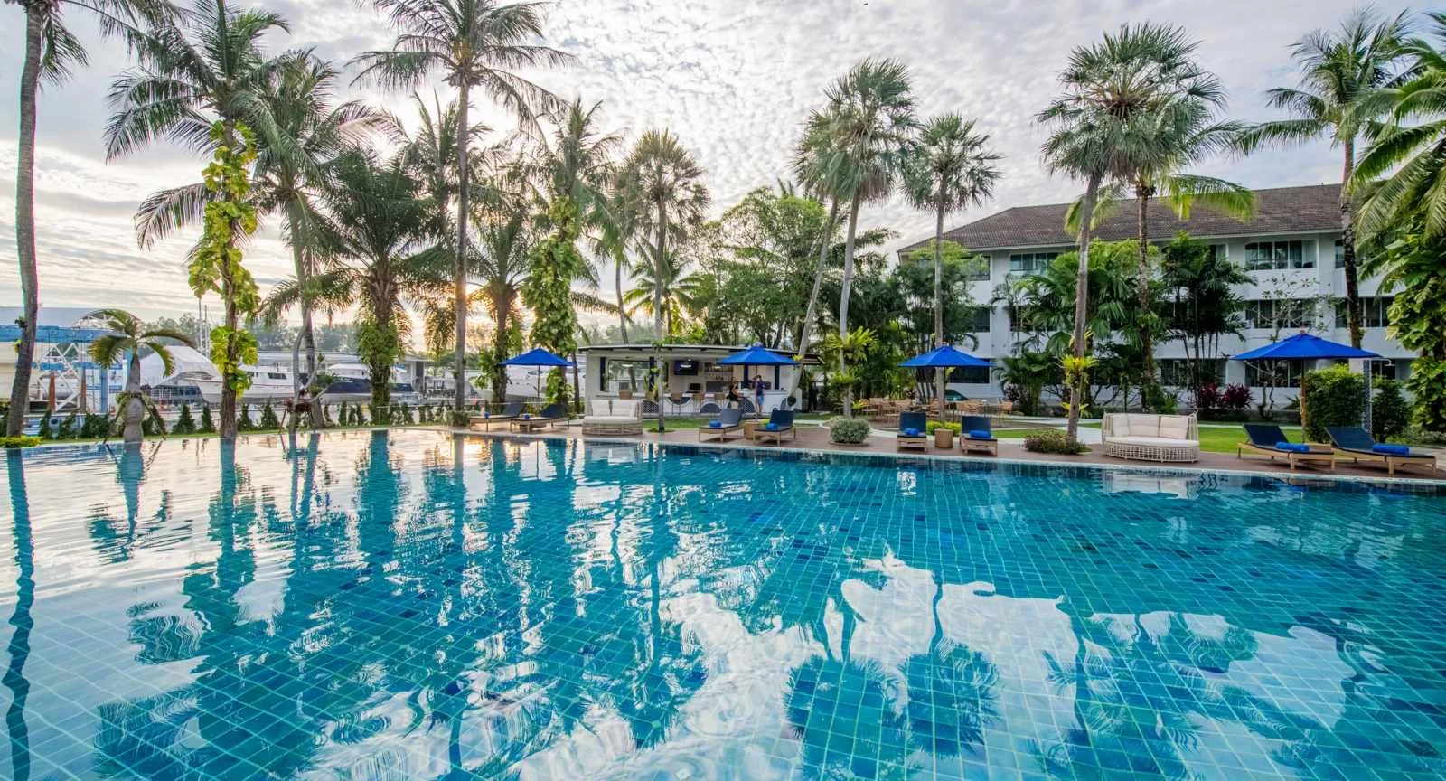 Palm-lined swimming pool with loungers at NH Boat Lagoon Phuket Resort