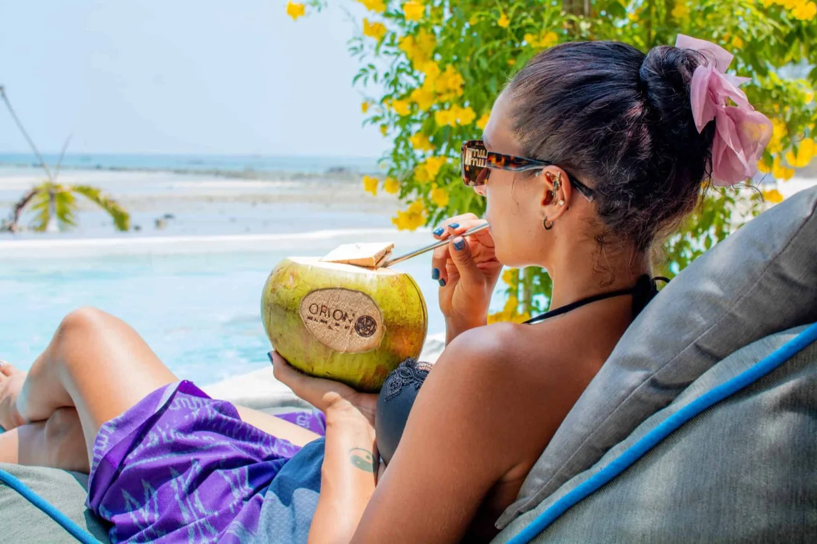 Guest drinking from a coconut on a beach lounger at Orion Healing Centre in Srithanu, Koh Phangan