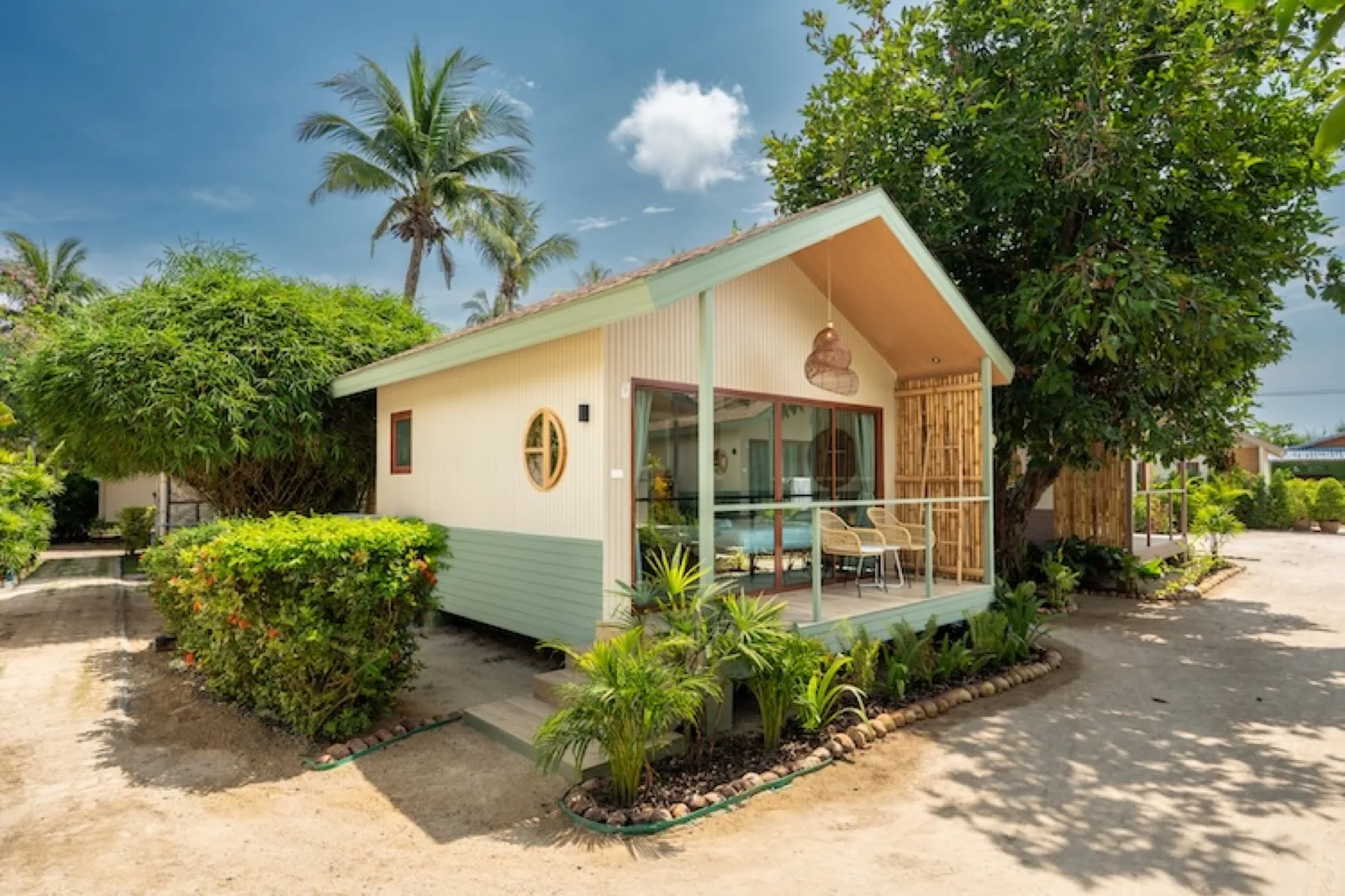 White bungalow with a terrace surrounded by tropical plants at Orion Healing Centre