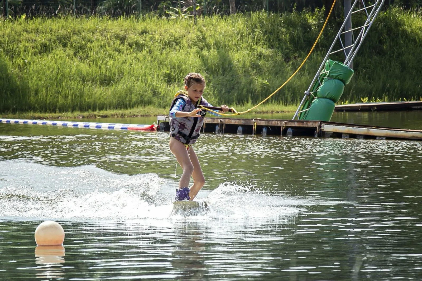 Young rider learning to wakeboard on the lake at Phuket Wake Park