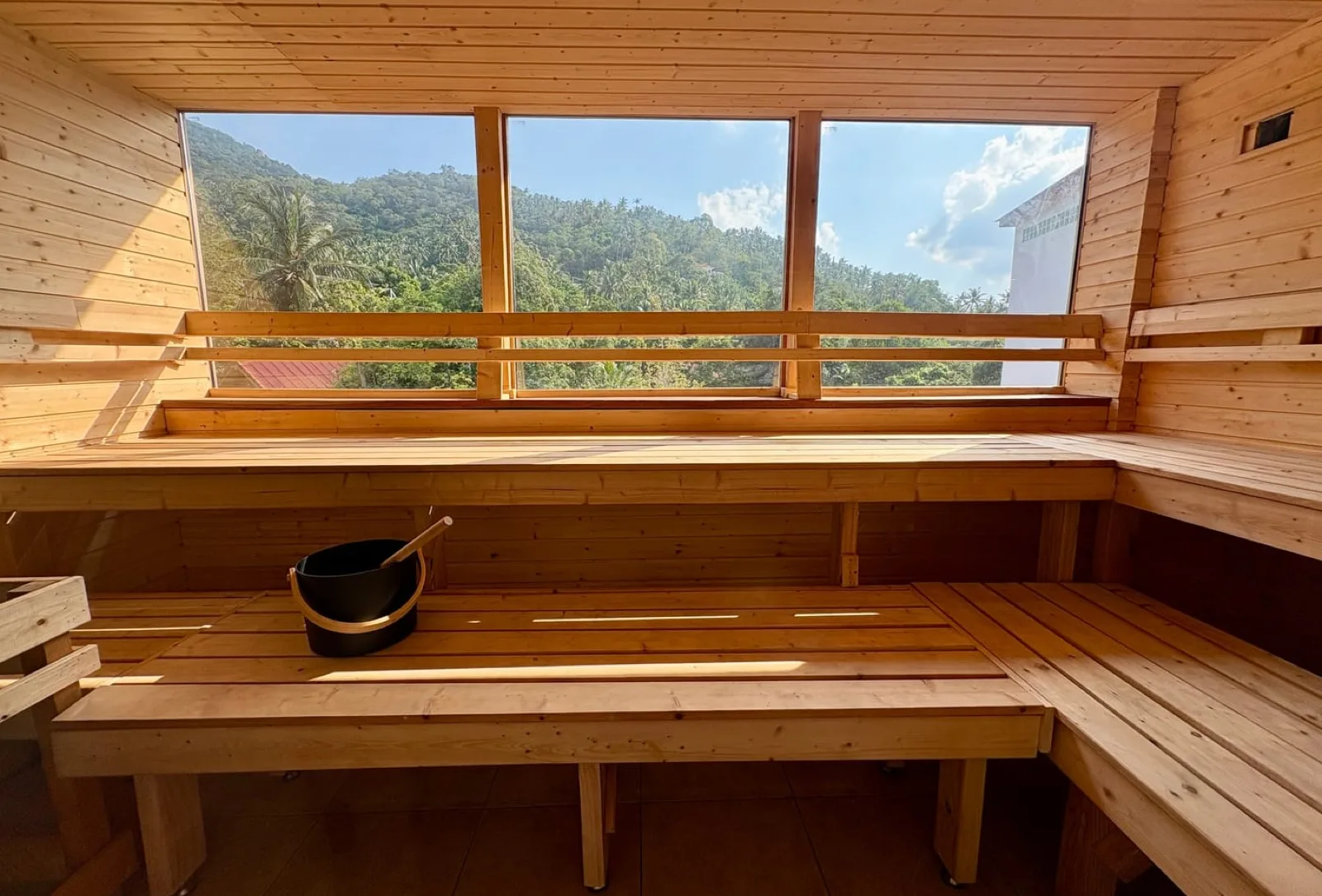 Wooden interior of the wood-fire sauna at Recovery Club Koh Tao with windows over the jungle