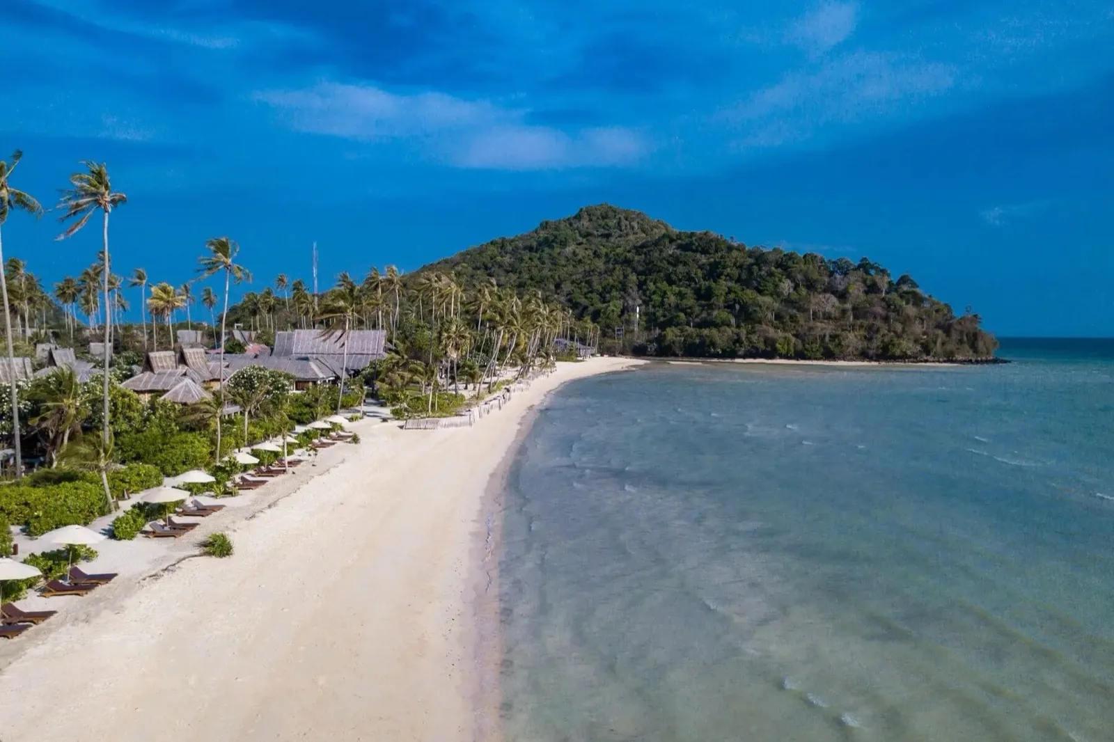Long empty beach in front of SAii Phi Phi Island Village with sunbeds under the palms on Phi Phi Don