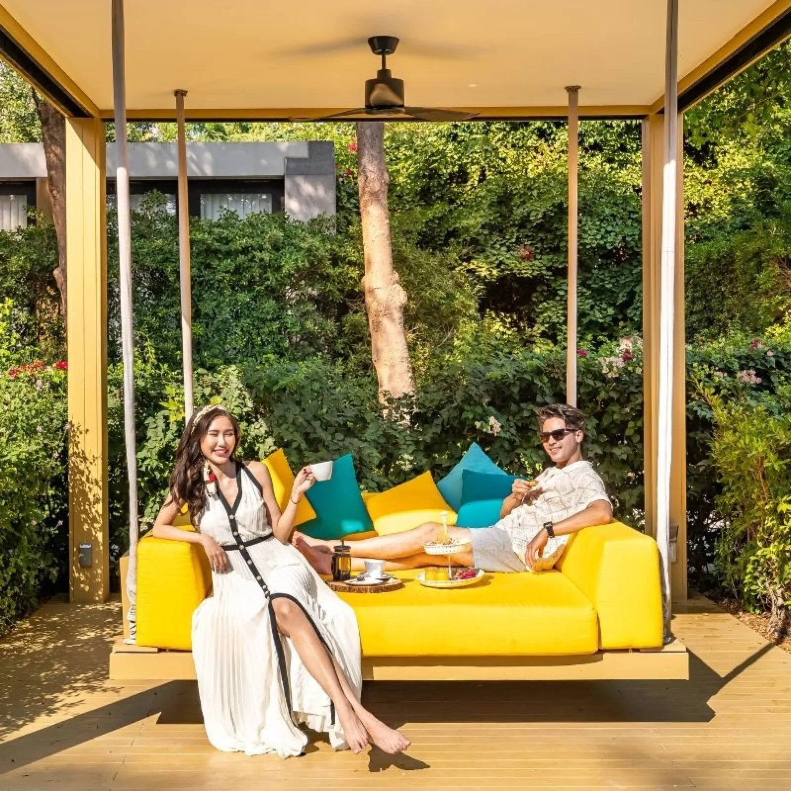 Couple relaxing on a yellow daybed in a garden cabana at SO/ Sofitel Hua Hin