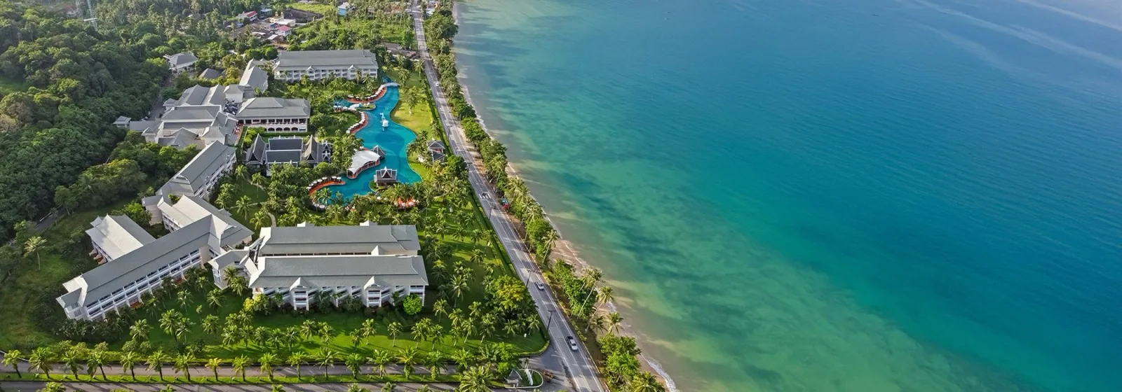 Wide aerial view of Sofitel Krabi Phokeethra and its lagoon pool beside the Klong Muang coastline