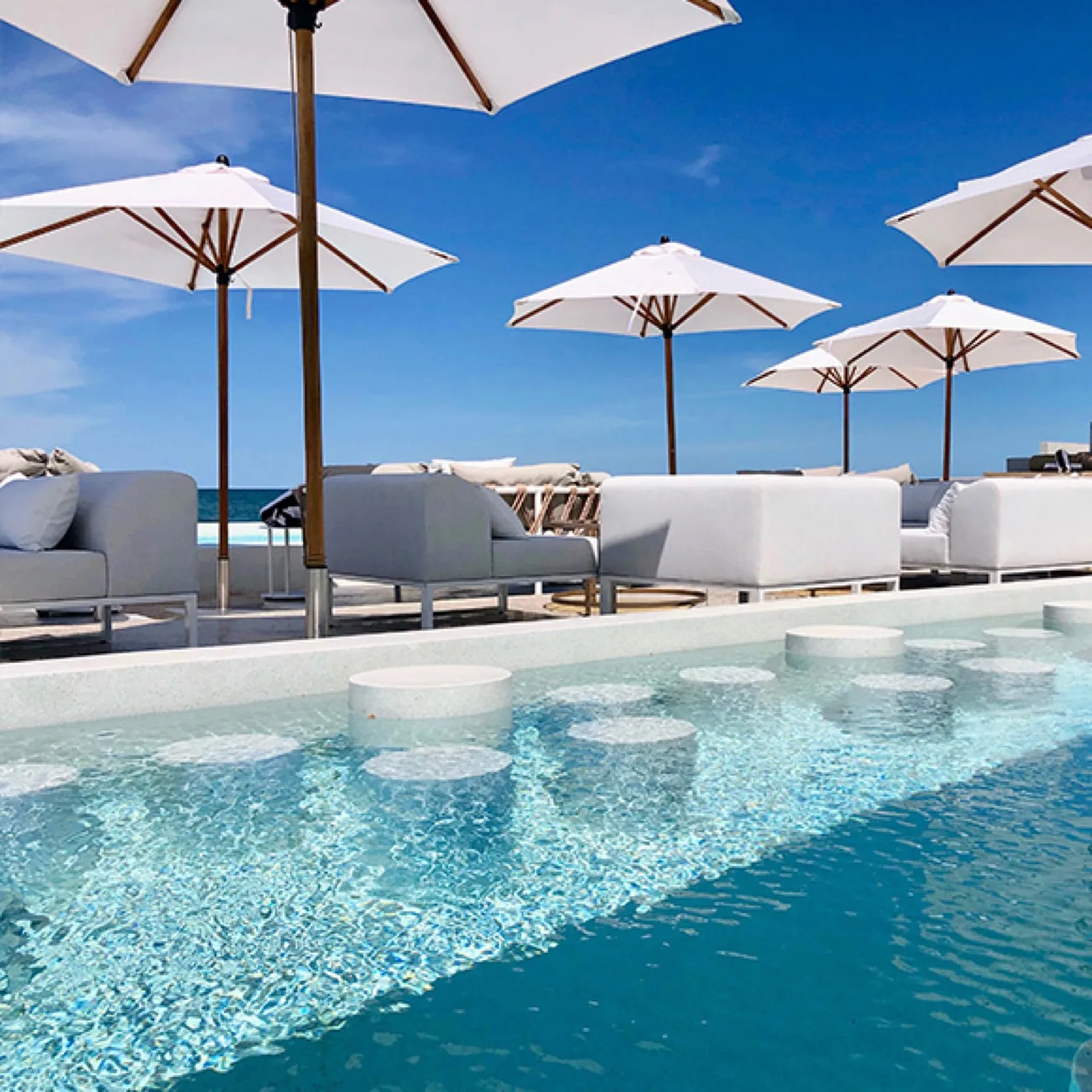 Infinity pool with in-water seats and white parasols at Sundance Dayclub Hua Hin