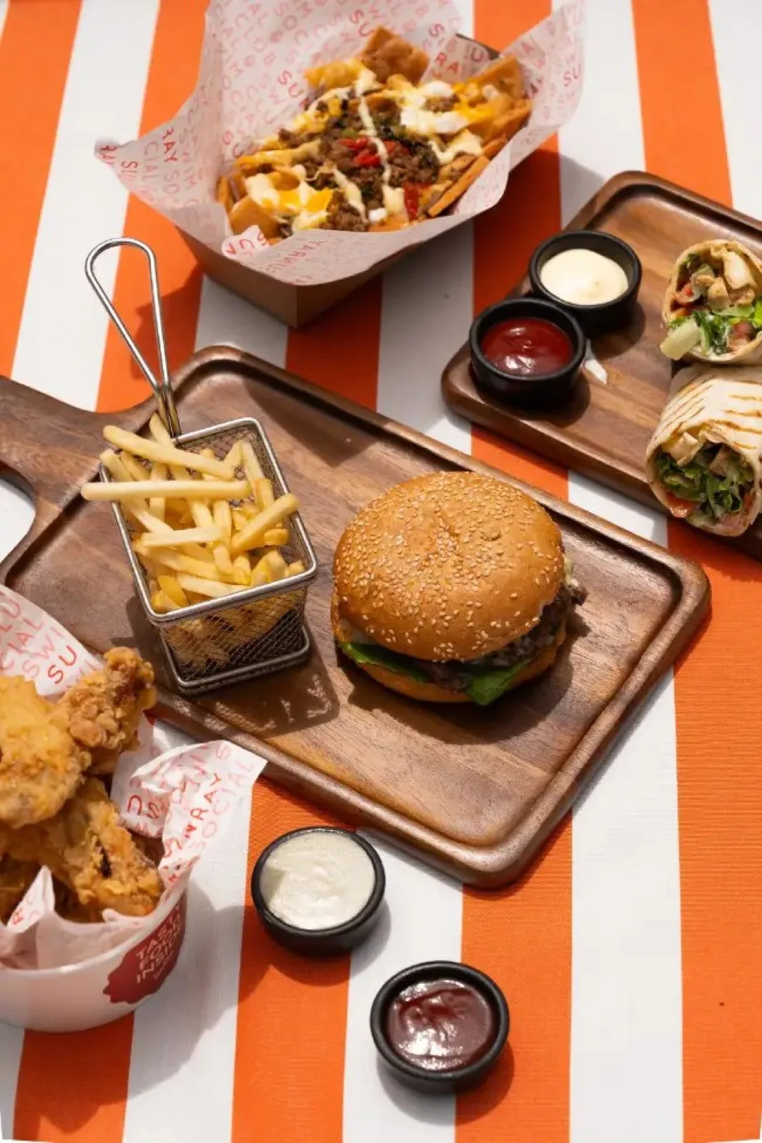 Burger, fries and sharing snacks on an orange striped table at SunRay Koh Samui