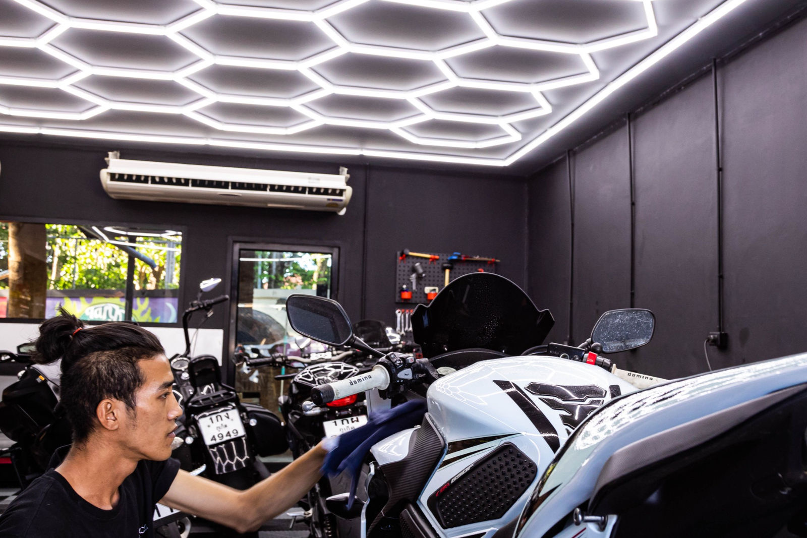 A mechanic detailing a motorbike in the wash bay at Tank and Throttle Co. in Chalong, Phuket