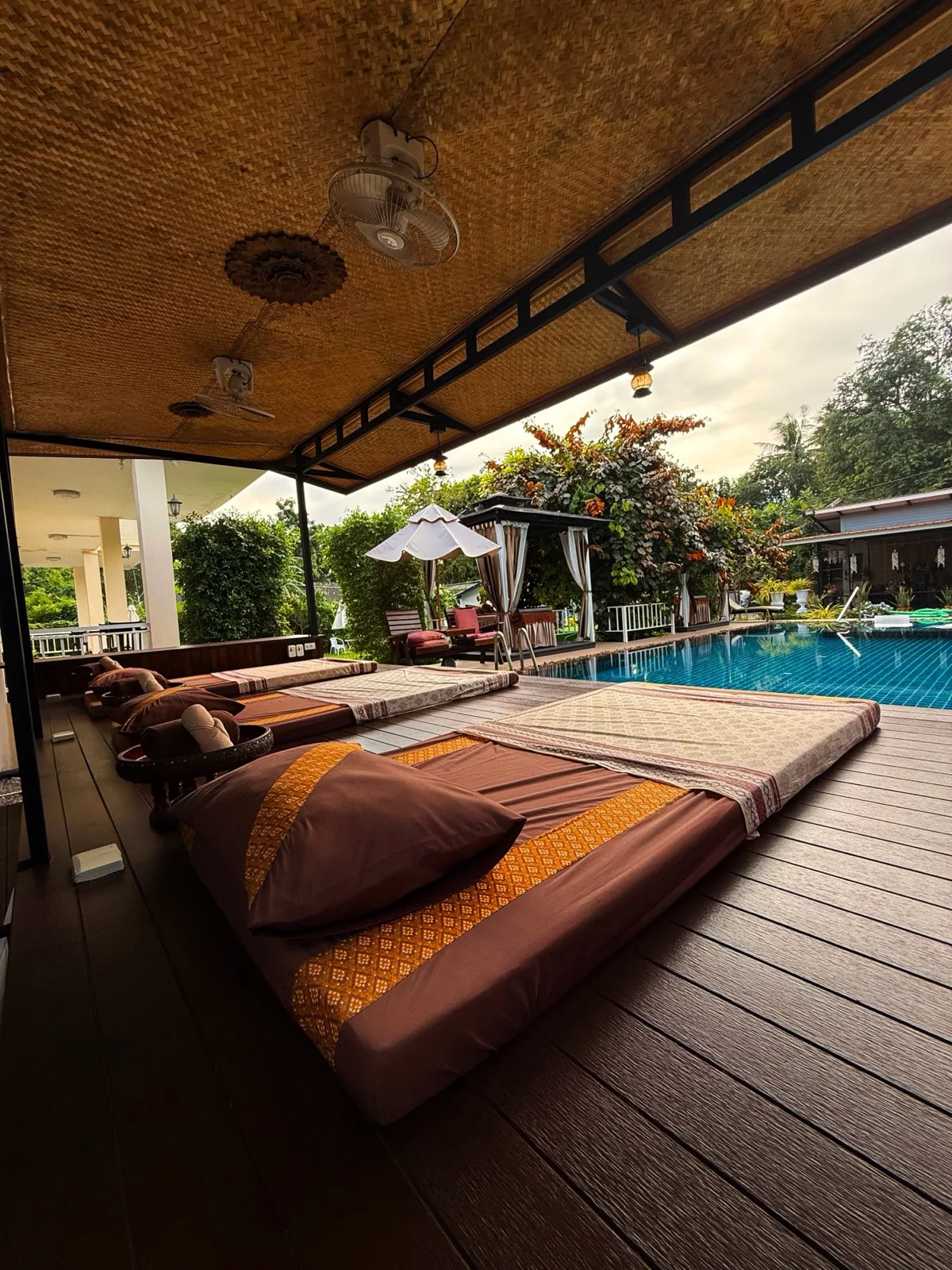 Massage mattresses in a covered sala beside the pool at The Cottage Retreat