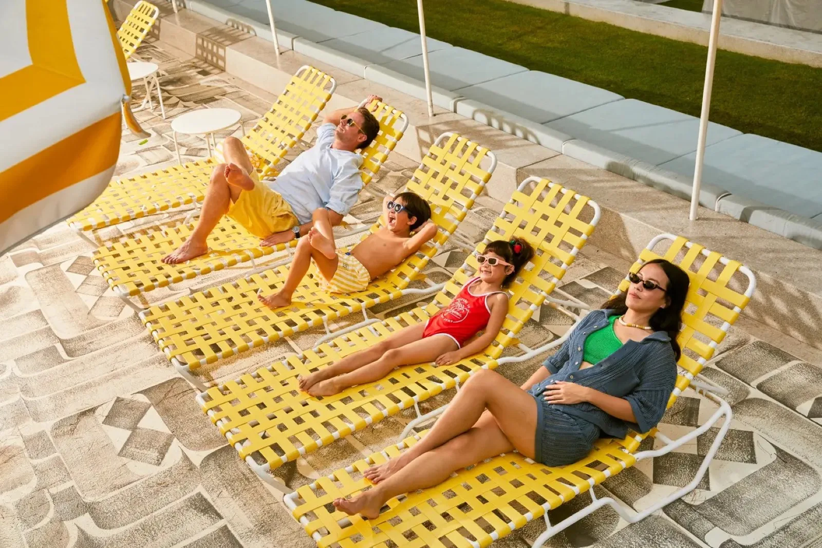 Family relaxing on yellow loungers on the pool deck at The Standard Hua Hin