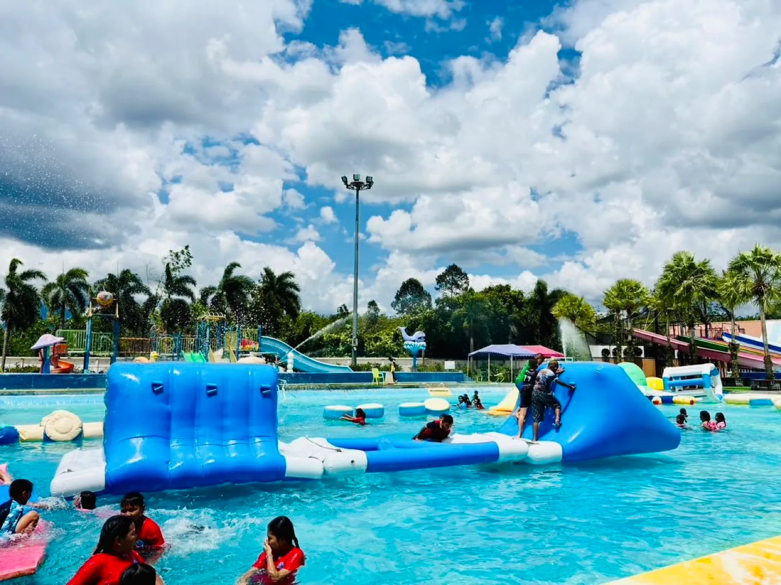 Blue inflatable course and palm trees in the big pool at Thung Song Water Park