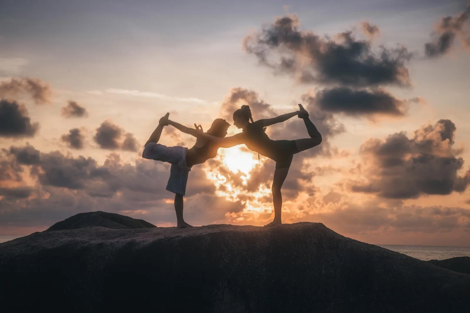 Yoga poses on the rocks at sunrise at Vikasa Koh Samui