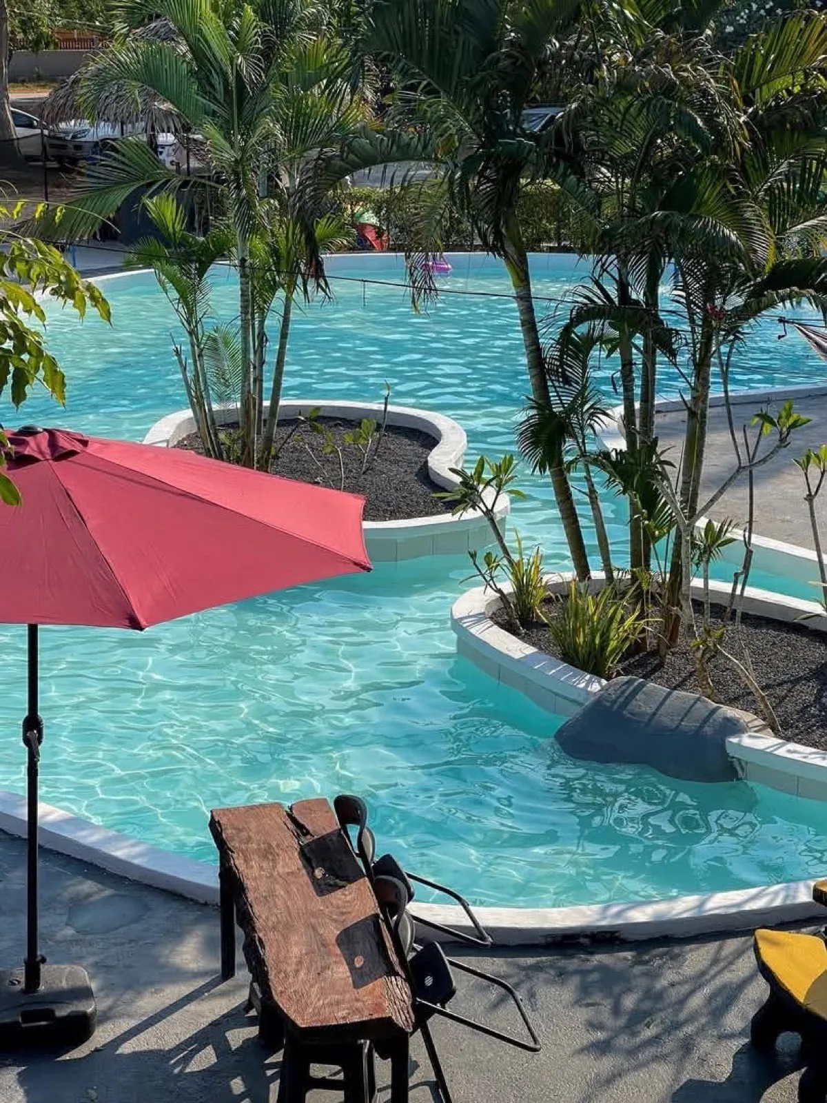 Lagoon pool with planted islands and a red parasol at Warehouse18, Don Sak