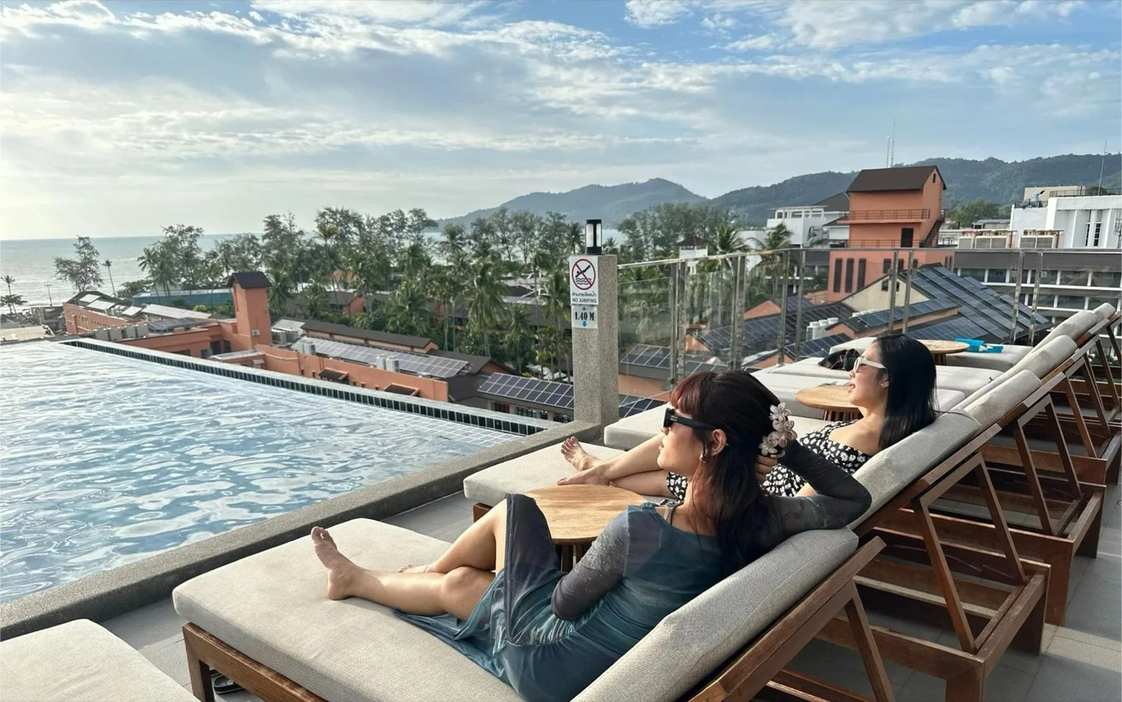 Guests relaxing on loungers beside the rooftop infinity pool at YouDee Hotel Patong, Phuket